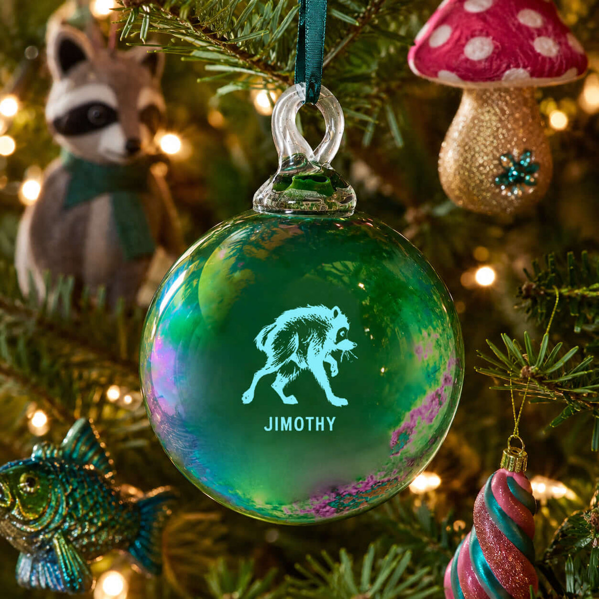 Glass ornament featuring Jimothy, the city's favorite dumpster king, hanging on a festive tree.